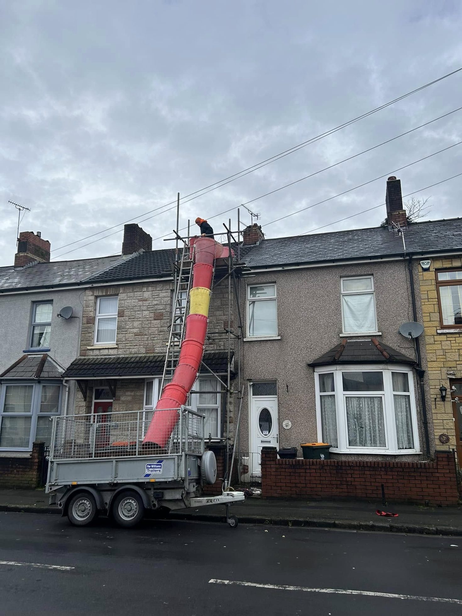 Roof repair site with scaffolding and debris chute set up on a residential property