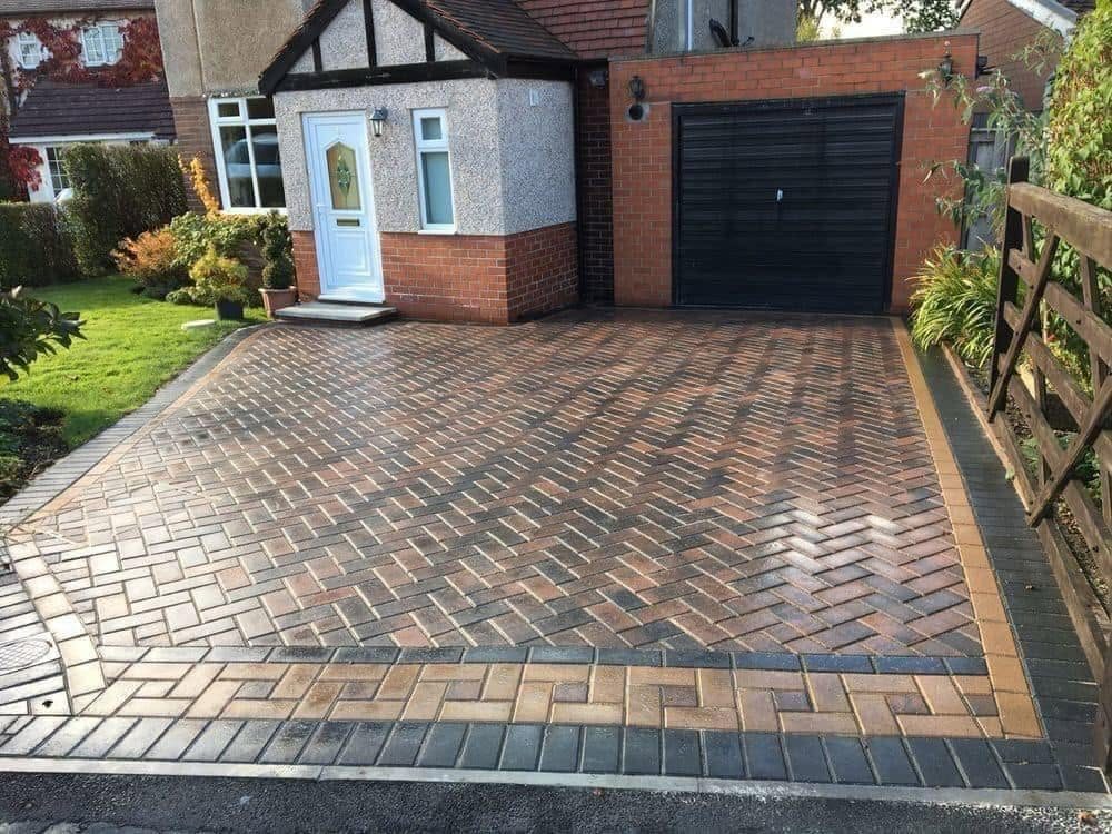 Patterned red block paving driveway leading up to a garage