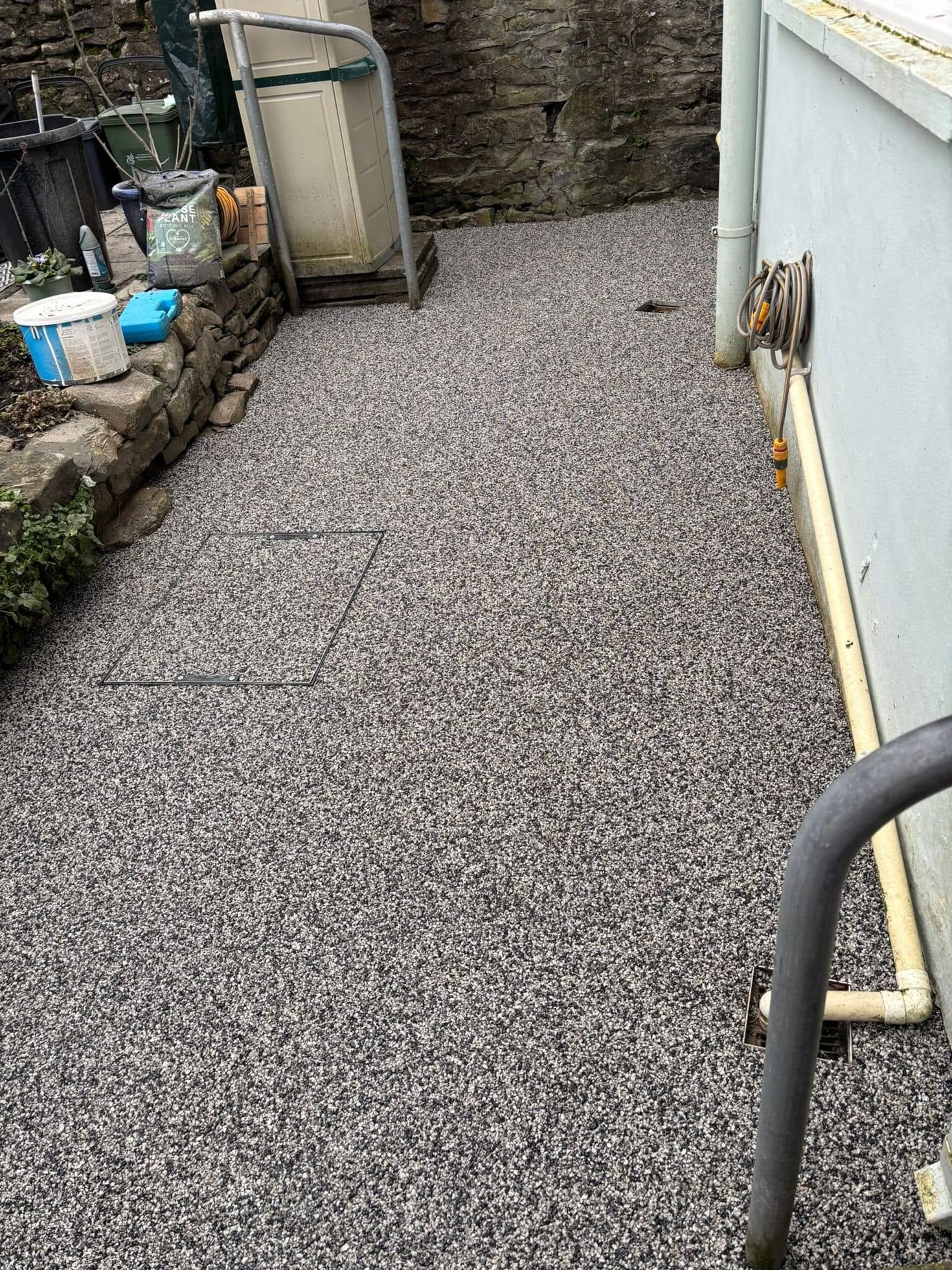 Resin bound path and rear yard finished beside a stone garden wall