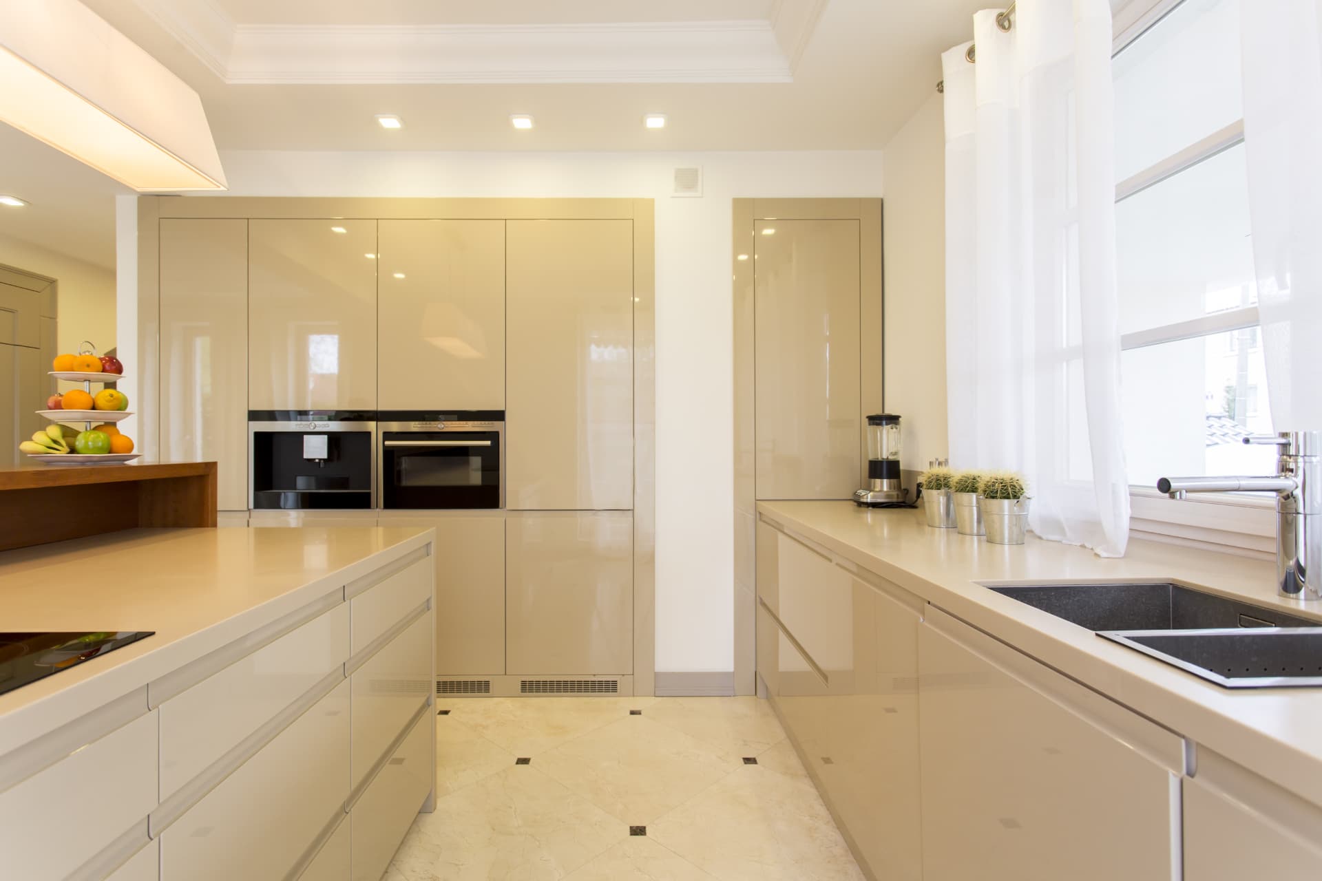 Newly fitted modern kitchen with gloss units, integrated ovens and stone worktops