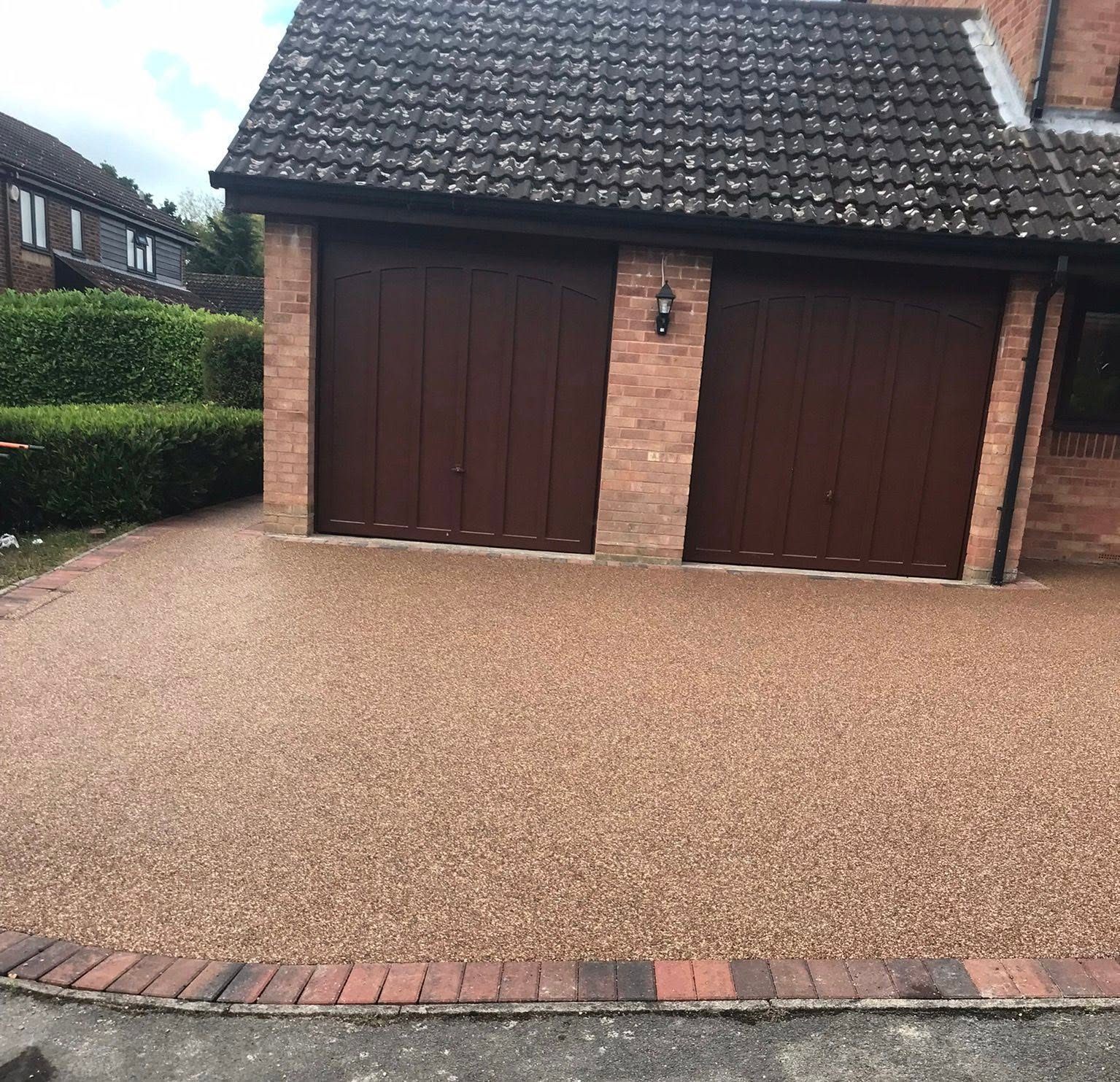 Tan resin bound driveway laid in front of a double garage in South Wales