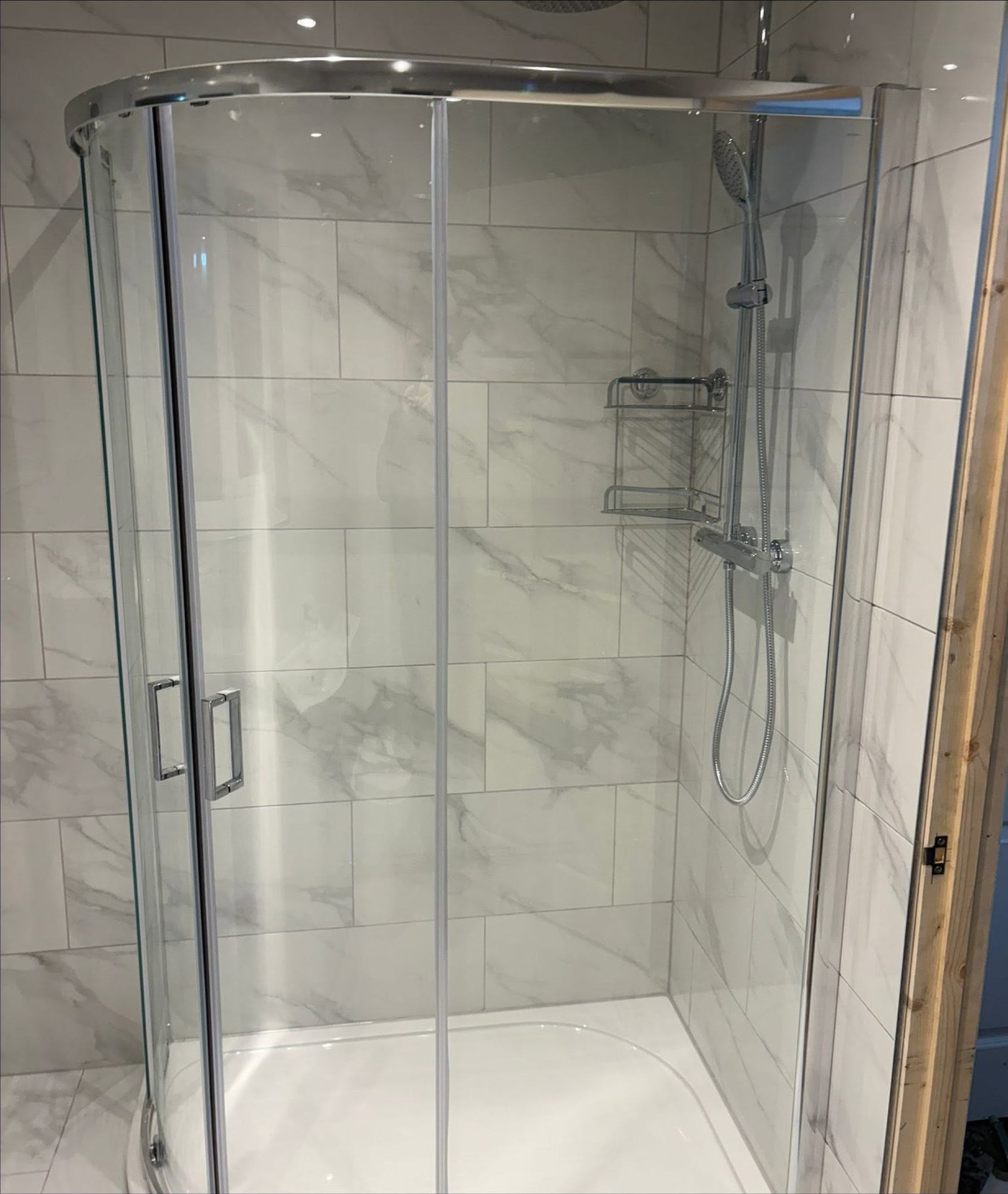 Glass shower enclosure with chrome shower fittings in a newly fitted bathroom