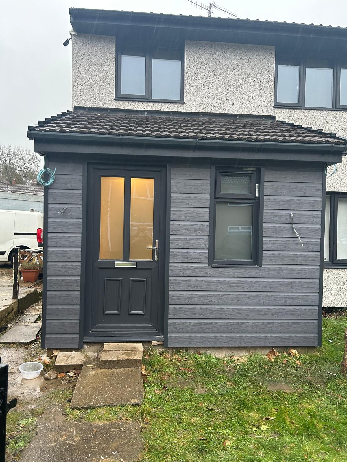 Grey clad garden extension with a dark door and window
