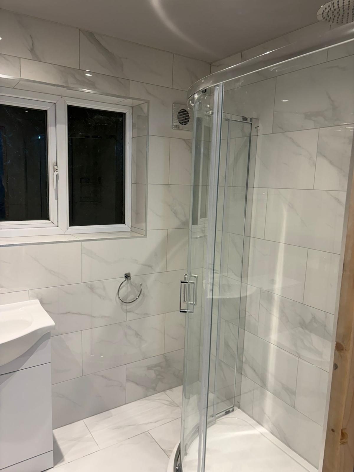 Bathroom with glass shower enclosure, tiled walls and chrome fittings