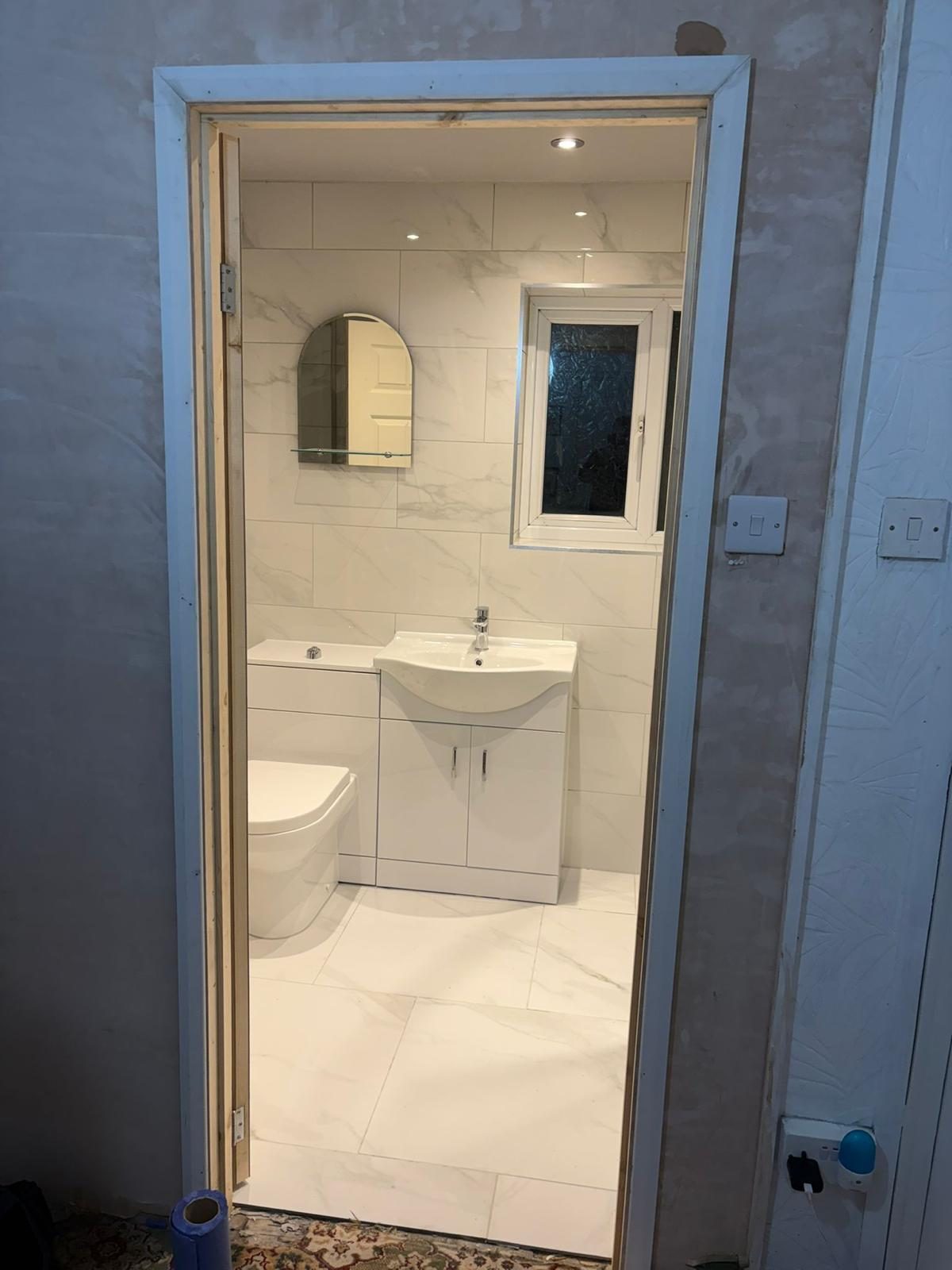 Bathroom refit viewed from the landing showing finished tiling, toilet, sink and flooring
