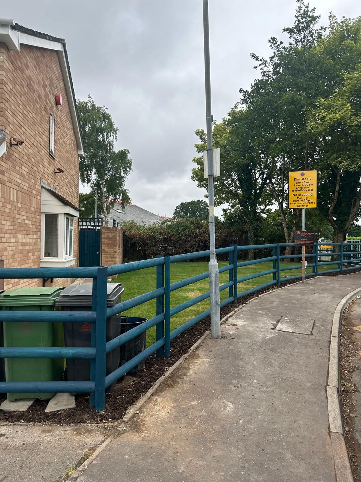 New painted post and rail timber fence beside a tidy lawn and footpath
