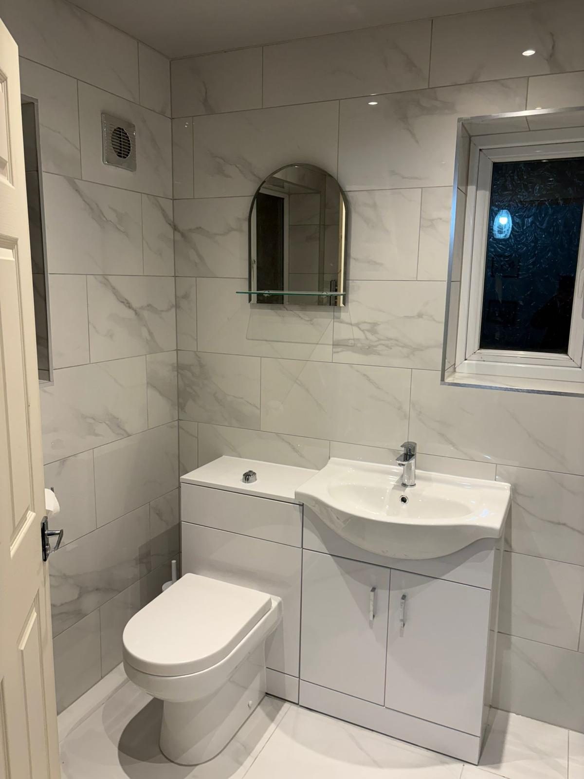 Finished tiled bathroom with vanity sink, toilet, mirror and extractor fan